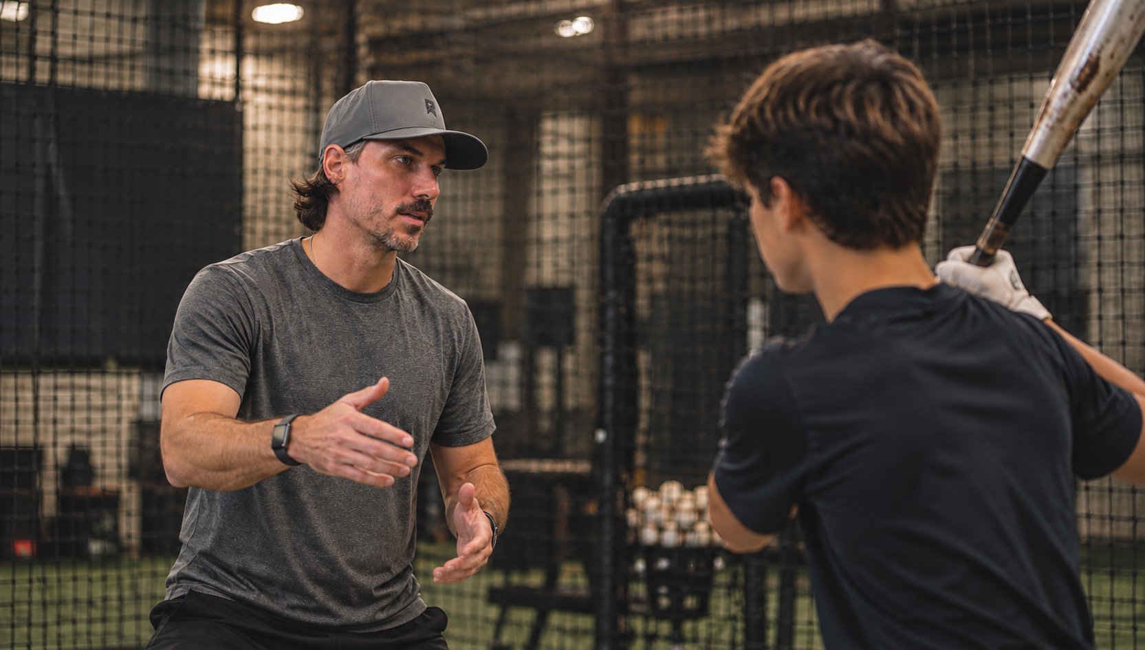 Justin Sizemore talking with a hitter behind the batting cage